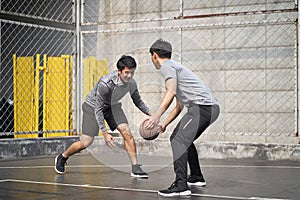 Two young asian men playing basketball outdoors