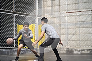 Two young asian men playing basketball outdoors