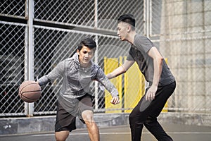 Two young asian men playing basketball outdoors