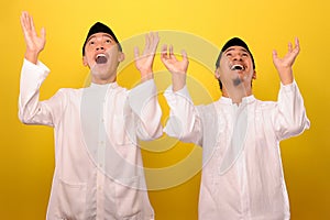 Two Young Asian Muslim men protecting themselves with outstretched hands from something getting to them from above