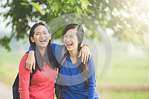 Two young Asian students laugh, joking around together