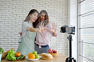 Two young asian woman food bloggers talking while recording video, vlog concept, people and technology communication