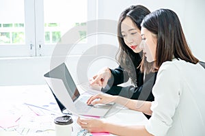 Two young asian women in office working and happy together on desktop