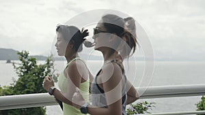 two young asian women running outdoors by the sea