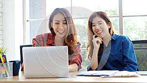 Two young asian women working with laptop computer at home office with happy emotion moment, working at home, small business,