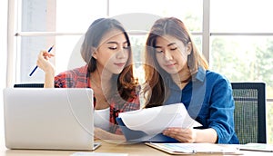 Two young asian women working with laptop computer at home office with happy emotion moment, working at home, small business,