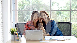 Two young asian women working with laptop computer at home office with happy emotion moment, working at home, small business,