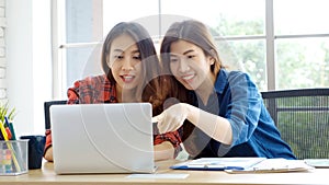 Two young asian women working with laptop computer at home office with happy emotion moment, working at home, small business,