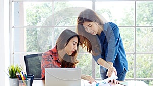 Two young asian women working with laptop computer at home office with happy emotion moment, working at home, small business,