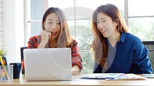 Two young asian women working with laptop computer at home office with happy emotion moment, working at home, small business,