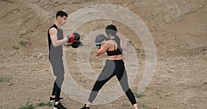 Two Young Athletes Wearing Black Sportswear and Boxers Equipment, Man Teaching Woman Kickboxing, Healthy Lifestyle and