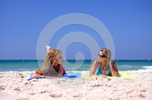 Two, young, attractive women lying on a beach