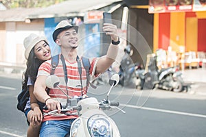 Two young backpackers taking selfies using mobilephones camera w