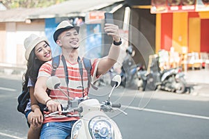 Two young backpackers taking selfies using mobilephones camera w photo