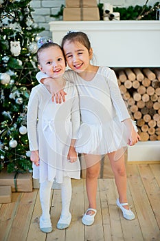 Two young ballet dancer hug near Christmas tree