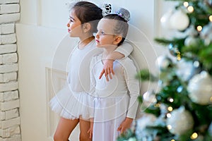 Two young ballet dancer hug near Christmas tree