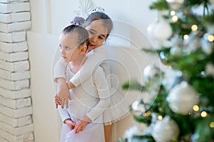 Two young ballet dancer hug near Christmas tree