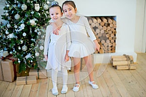 Two young ballet dancer hug near Christmas tree