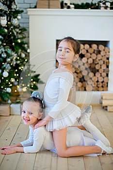 Two young ballet dancer sitting near Christmas tree