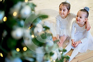 Two young ballet dancer sitting near Christmas tree
