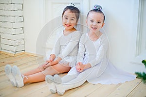 Two young ballet dancer sitting near Christmas tree