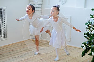 Two young ballet dancers learning the lesson near Christmas tree