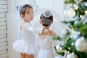 Two young ballet dancers learning the lesson near Christmas tree