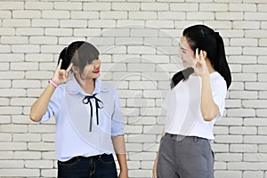 Two young and beautiful Asain women learning and displaying the skill of deaf people communication, hand and sign language