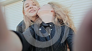 Two young beautiful girlfriends blonde fun and coquettish posing in front of the camera. Do selfie. Spring.