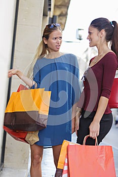 Two young beautiful girls criticizing store window