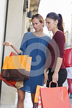 Two young beautiful girls criticizing store window