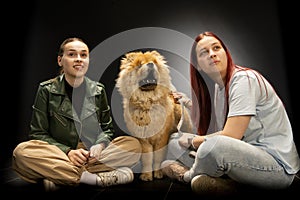 Two young, beautiful girls are having fun with a chow chow dog