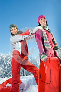 Two young beautiful girls with sledges