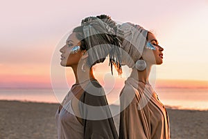 Two young beautiful girls in turban on the beach at sunset