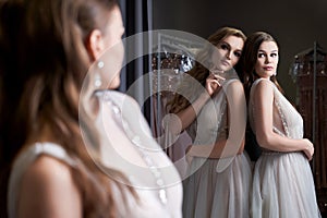 Two young beautiful girls wearing a full-length silver white chiffon prom ball gowns decorated with sparkles and sequins