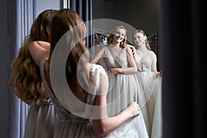Two young beautiful girls wearing a full-length silver white chiffon prom ball gowns decorated with sparkles and sequins