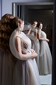 Two young beautiful girls wearing a full-length silver white chiffon prom ball gowns decorated with sparkles and sequins