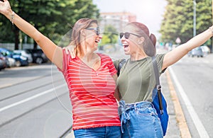 Two young beautiful  smiling girls in a summer day whit colored t-shirt clothes and jeans