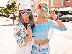 Two young beautiful smiling hipster girls in trendy summer clothes