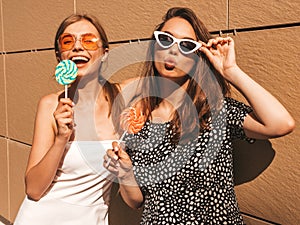 Two young beautiful smiling hipster girls in trendy summer clothes