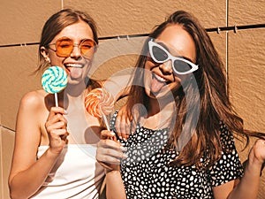 Two young beautiful smiling hipster girls in trendy summer clothes