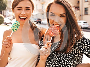 Two young beautiful smiling hipster girls in trendy summer clothes