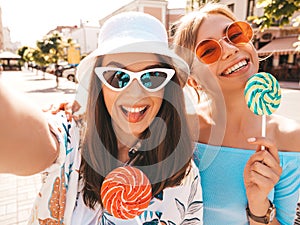 Two young beautiful smiling hipster girls in trendy summer clothes