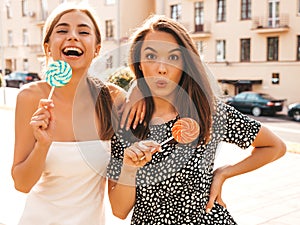 Two young beautiful smiling hipster girls in trendy summer clothes