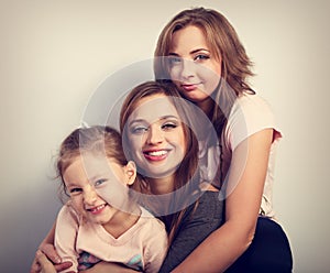 Two young beautiful smiling women and happy joying kid girl hugging with love. Toned closeup portrait