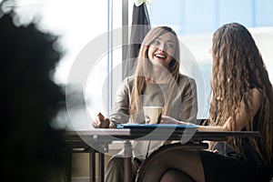 Two young beautiful women chatting in cafe