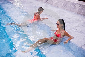 Two young beautiful women in jacuzzi of resort