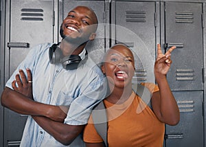 Two young black students pose with silly faces in front of campus lockers