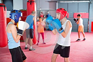 Two young boxer wearing gloves and helmet sparring