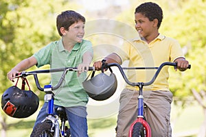 Two young boys on bicycles outdoors smiling